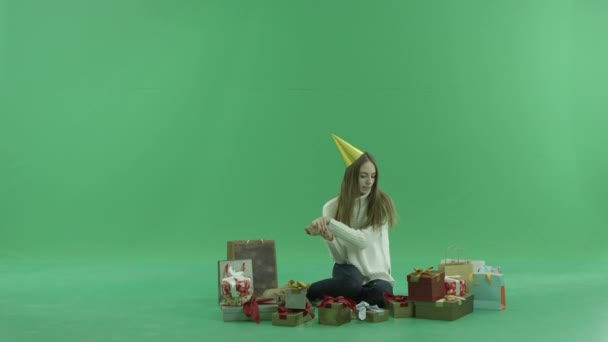 Jolie jeune femme regardant sur ses cadeaux de Noël et sacs à provisions, clé chromatique sur fond — Video