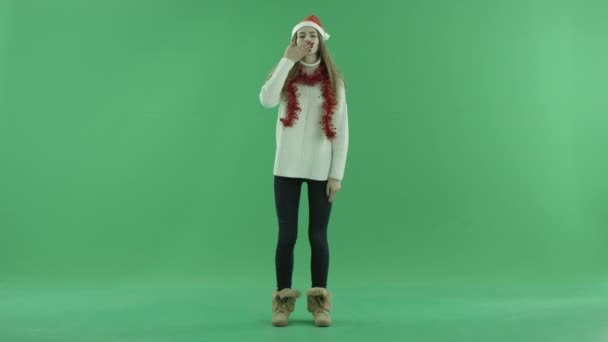 Sexy young beauty in Christmas hat sends air kisses, chroma key on background — Stock Video