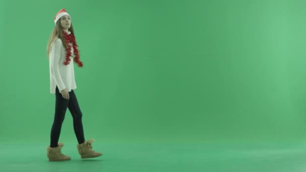 迷人的年轻美女在圣诞帽散步和使用虚拟屏幕, 色度键的背景 — 图库视频影像