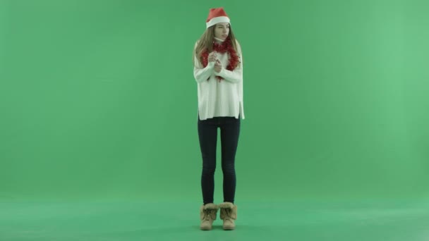 Noel şapka içinde muhteşem kadın donuyor ve kendini sıcak, chroma anahtar arka plan üzerinde tutmaya çalışıyor — Stok video