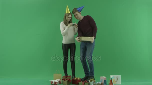 Young woman takes photo of Christmas gift while her man is holding it, chroma key on background — Stock Video