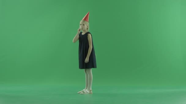 Kleines Mädchen mit Mütze bläst in Weihnachtspfeife, Chroma-Taste auf Hintergrund — Stockvideo