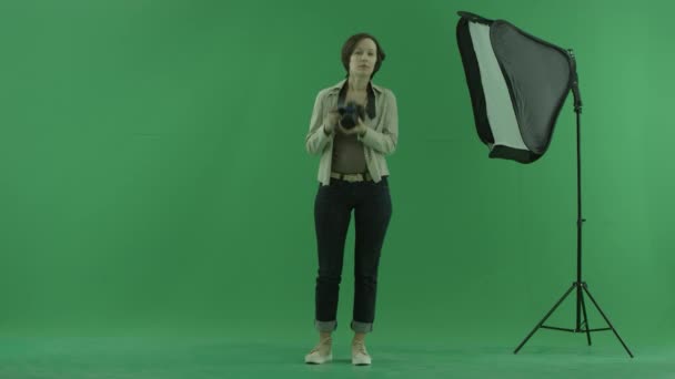 A young woman tries to take some photos of the viwer on the green screen — Stock Video