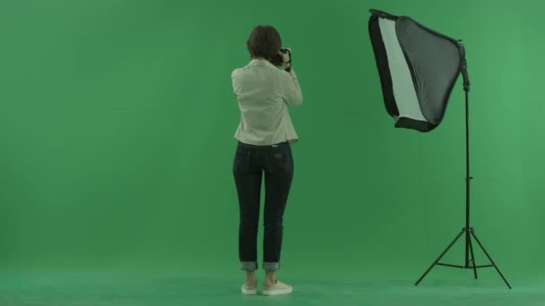 En ung kvinna att ta foton på sida tillbaka till betraktaren och göra vissa korrigeringar på grön skärm — Stockvideo