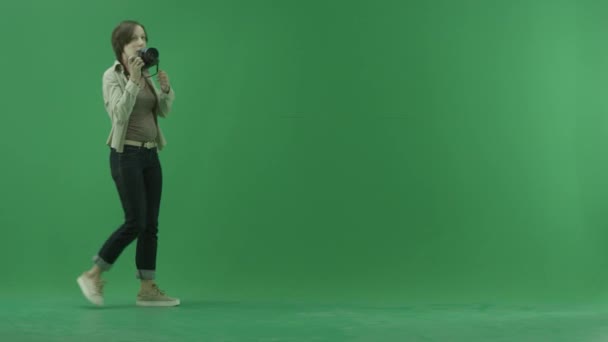 Een jonge vrouw gaat van de linker- en nemen van foto's om haar heen op het groene scherm — Stockvideo