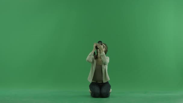 Sitting young woman is taking photos upper her on the green screen — Stock Video