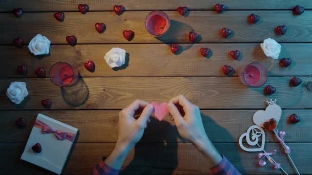 Interessanter Mann mit handgeschöpftem Herz aus Papier sitzt am Tisch, Draufsicht — Stockvideo