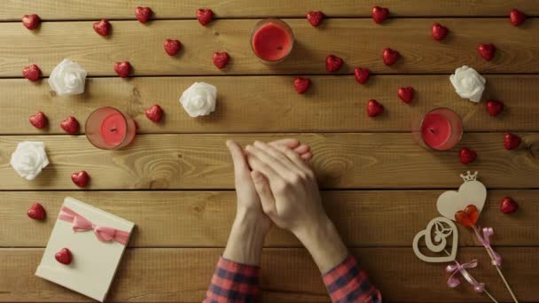 Jeune homme avec coeur en papier assis près d'une table en bois, vue de dessus — Video