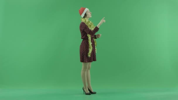 Μια νεαρή γυναίκα Χριστούγεννα είναι η αναζήτηση για κάτι σχετικά με μια μεγάλη οθόνη αφής στη δεξιά πλευρά στην πράσινη οθόνη — Αρχείο Βίντεο
