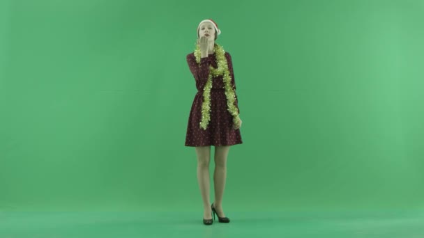 A young Christmas woman sends air kisses to the viewer on the green screen — Stock Video