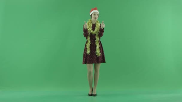 Μια νεαρή γυναίκα Χριστούγεννα δείχνει ότι κάτι είναι δροσερό στην πράσινη οθόνη — Αρχείο Βίντεο