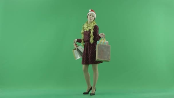 Ein junges Mädchen zeigt dem Betrachter auf dem grünen Bildschirm die Ergebnisse von Weihnachtseinkäufen — Stockvideo