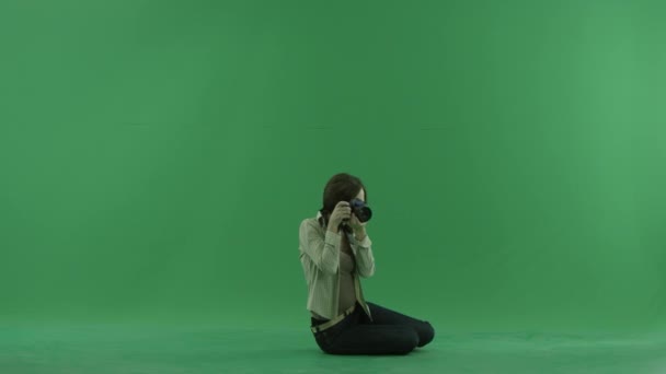 Sitzende junge Frau macht Fotos auf der rechten Seite auf dem grünen Bildschirm — Stockvideo