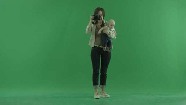 Mladá žena s dítětem fotografování kolem sebe na zelené obrazovce — Stock video
