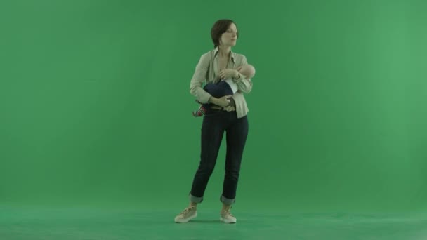 En ung kvinna stenar sin bebis på grön skärm — Stockvideo