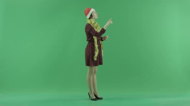 Una joven mujer de Navidad está buscando algo en una gran pantalla táctil en el lado derecho de la pantalla verde — Vídeos de Stock