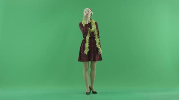 Een jonge vrouw van de kerst stuurt lucht kussen aan de kijker op het groene scherm — Stockvideo