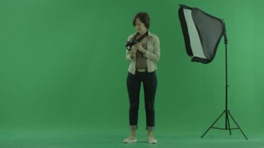 Genç bir kadın yeşil ekranda kamera kontrol eder.