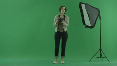 Genç bir kadın yeşil ekranda viwer bazı fotoğraf çekmek çalışır