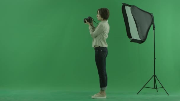 Μια νεαρή γυναίκα λήψη φωτογραφιών από την αριστερή πλευρά σχετικά με την πράσινη οθόνη — Αρχείο Βίντεο
