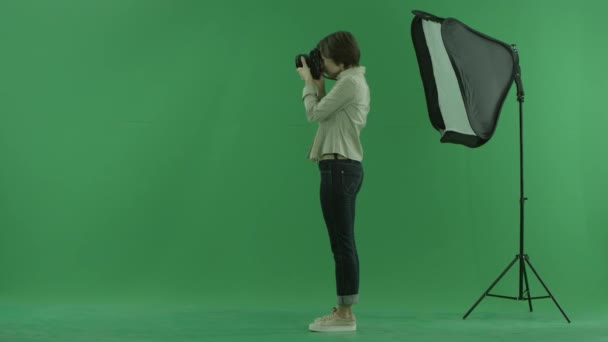 取る若い女性は緑色の画面の左側に写真し、モデルの地位を修正 — ストック動画