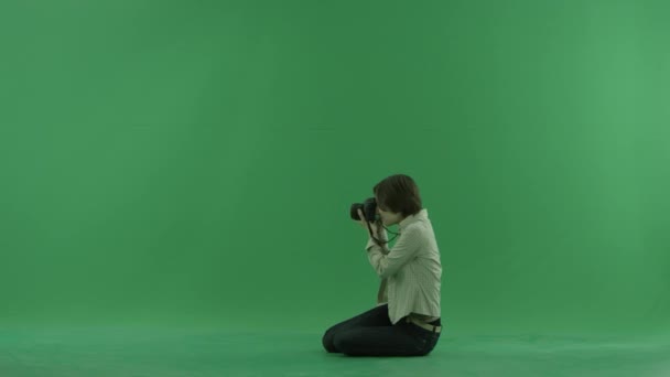 Giovane donna seduta sta scattando foto sul lato sinistro sullo schermo verde — Video Stock