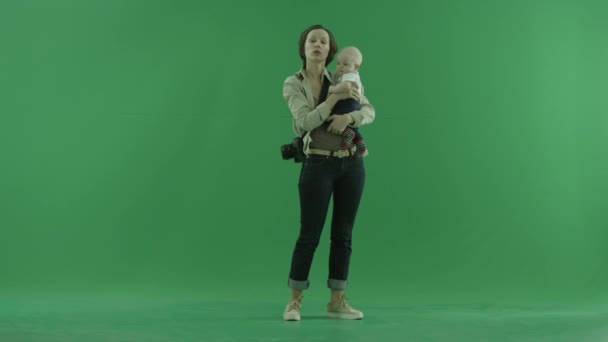 Een jonge vrouw gaat met haar baby op het groene scherm — Stockvideo