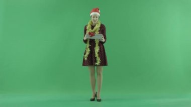 Genç bir kadın Christmasgift üstünde belgili tanımlık yeşil perde açıyor
