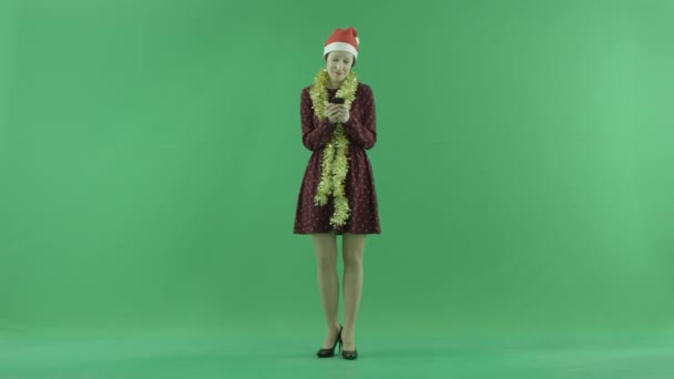 Una joven mujer de Navidad está escribiendo algo con su teléfono en la pantalla verde — Vídeos de Stock