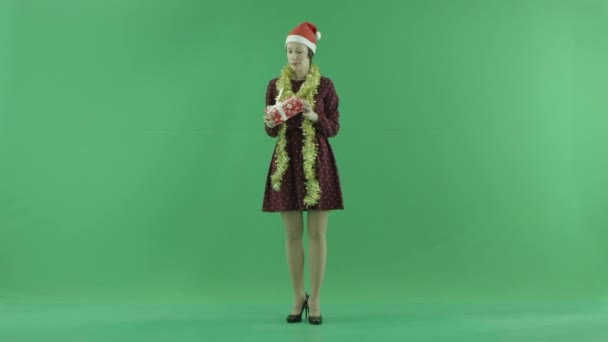 Eine junge Frau sucht ein Weihnachtsgeschenk und wirft es auf den grünen Bildschirm — Stockvideo