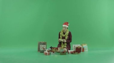Genç bir kadın oturuyor ve kendini yakın Noel hediyesi yeşil ekranda açma