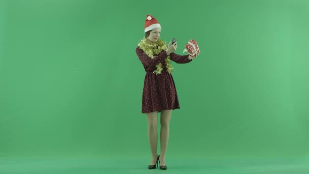 Eine junge Frau fotografiert ihr Weihnachtsgeschenk auf dem grünen Bildschirm — Stockvideo