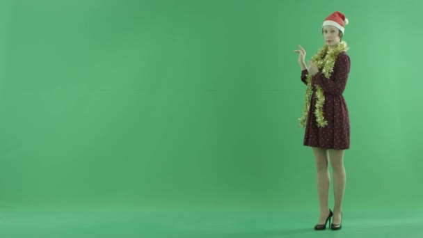 Een jonge vrouw van de kerst gaat over het weerbericht op de rechterkant van het groene scherm — Stockvideo