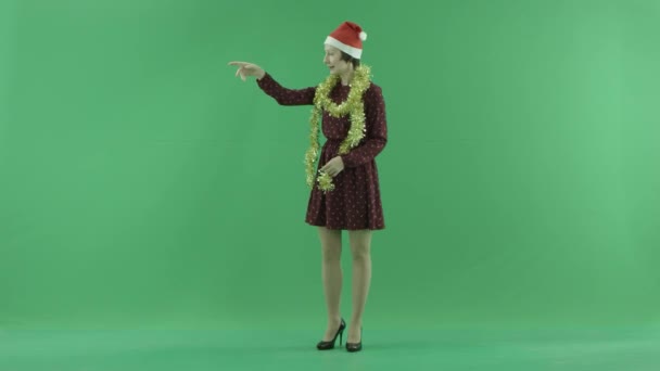 En ung kvinna som jul samtal till någon från vänster sida på grön skärm — Stockvideo