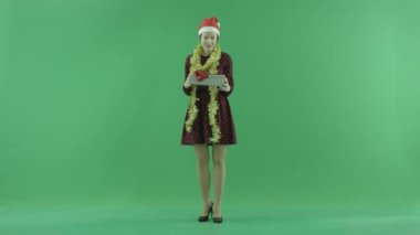 Genç bir kadın Christmasgift üstünde belgili tanımlık yeşil perde açıyor