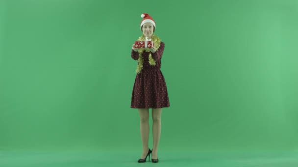 En ung kvinna är att ge en julklapp för en betraktare på grön skärm — Stockvideo