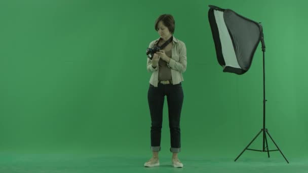 En ung kvinna kontrollerar kamera på grön skärm — Stockvideo