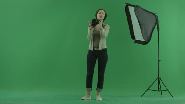 A young woman taking photos of a viewer on the green screen and correct his standing — Stock Video