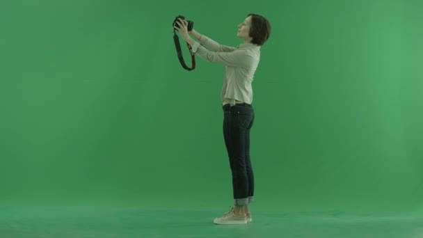 A young woman is taking photos of herself on the left hand side on the green screen — Stock Video