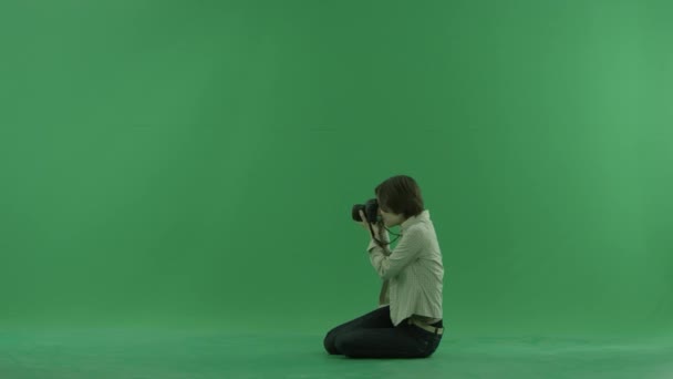 Jonge vrouw zitten is het nemen van foto's aan de linker kant op het groene scherm — Stockvideo