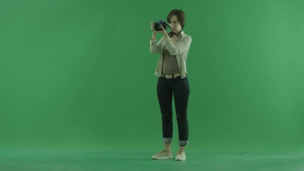 Eine junge Frau stimmt ihre Kamera auf den grünen Bildschirm ab — Stockvideo