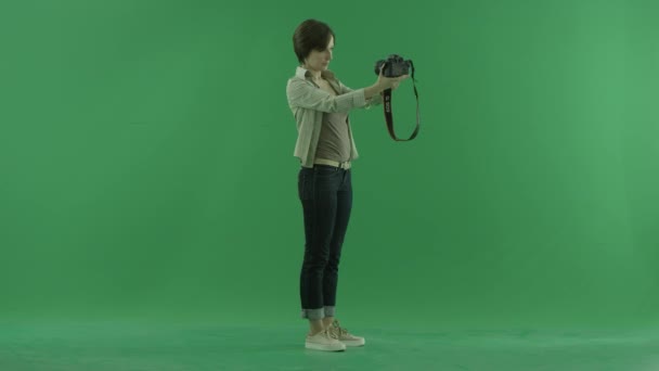 Uma jovem está tirando fotos de si mesma no lado direito na tela verde — Vídeo de Stock