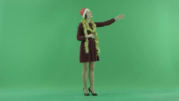 Una joven mujer de Navidad llama a alguien del lado derecho en la pantalla verde — Vídeos de Stock