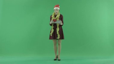 Genç bir kadın Christmasgift üstünde belgili tanımlık yeşil perde açıyor