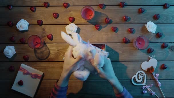Дорослий чоловік вставляє м'якого кролика в подарункову коробку як подарунок на день Святого Валентина, вид зверху — стокове відео