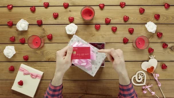 L'uomo mette la carta di credito nella confezione regalo come regalo, vista dall'alto — Video Stock