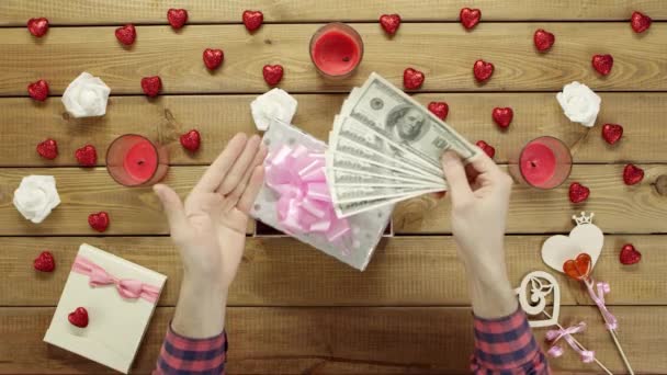 Человек кладет наличные деньги в подарочную коробку в качестве подарка для своего брата, вид сверху — стоковое видео