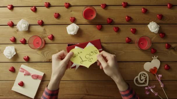 Jovem coloca papel valentine na caixa presente, vista superior — Vídeo de Stock
