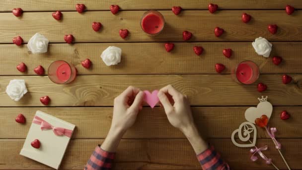 Glad man med handgjort hjärta papper sitter vid bordet, ovanifrån — Stockvideo