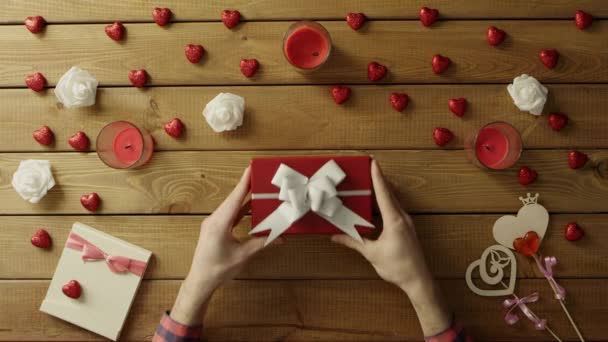 Adult man gets holiday present in gift box on wooden table, top view — Stock Video